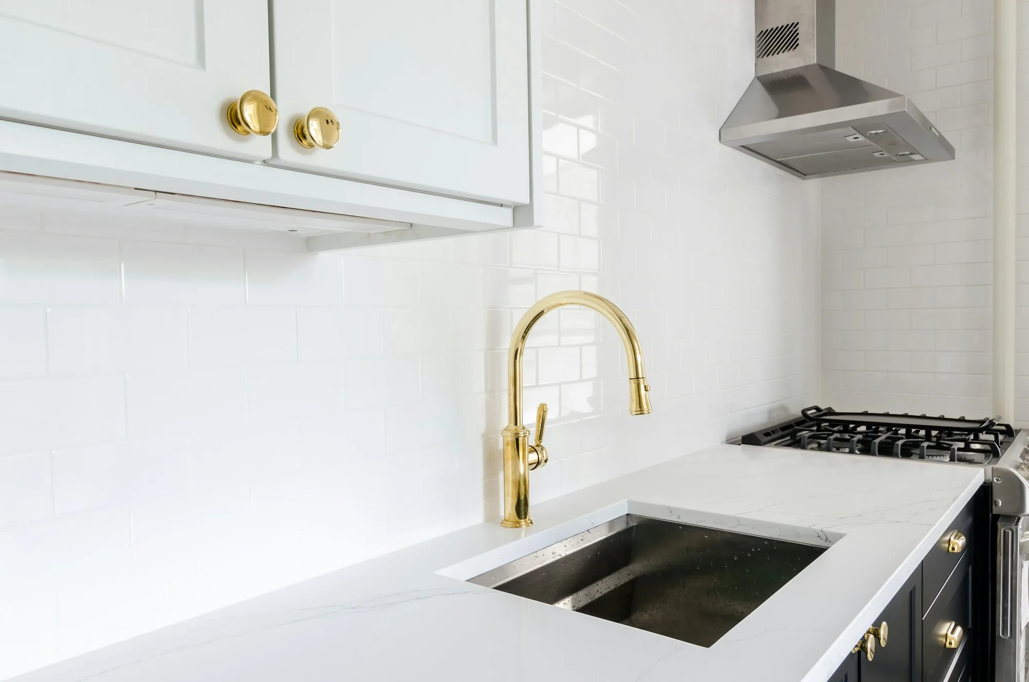 Bright white kitchen with a gold faucet and gas range