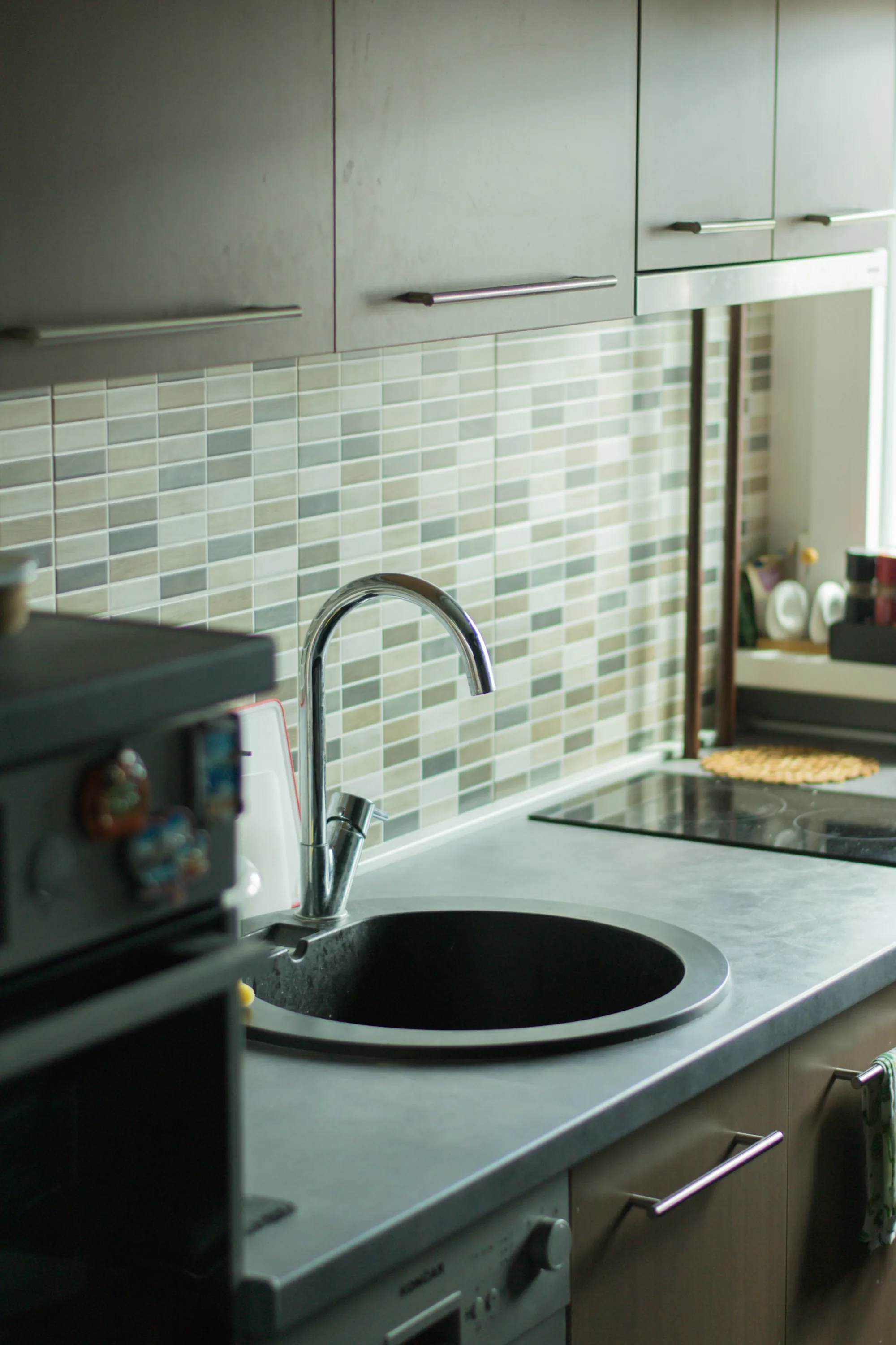 Brushed faucet against green tile in a modern kitchen