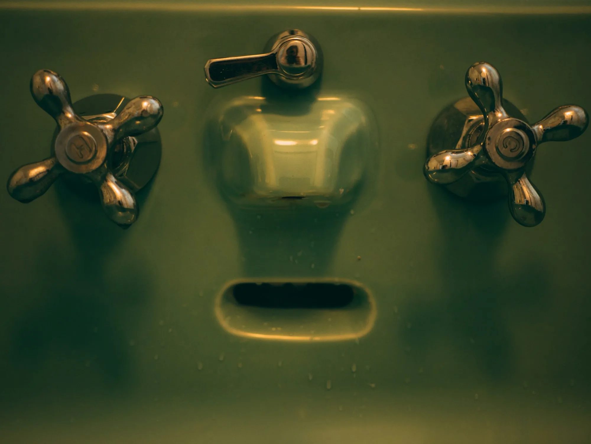 Vintage brass taps above a basin marked by mineral staining