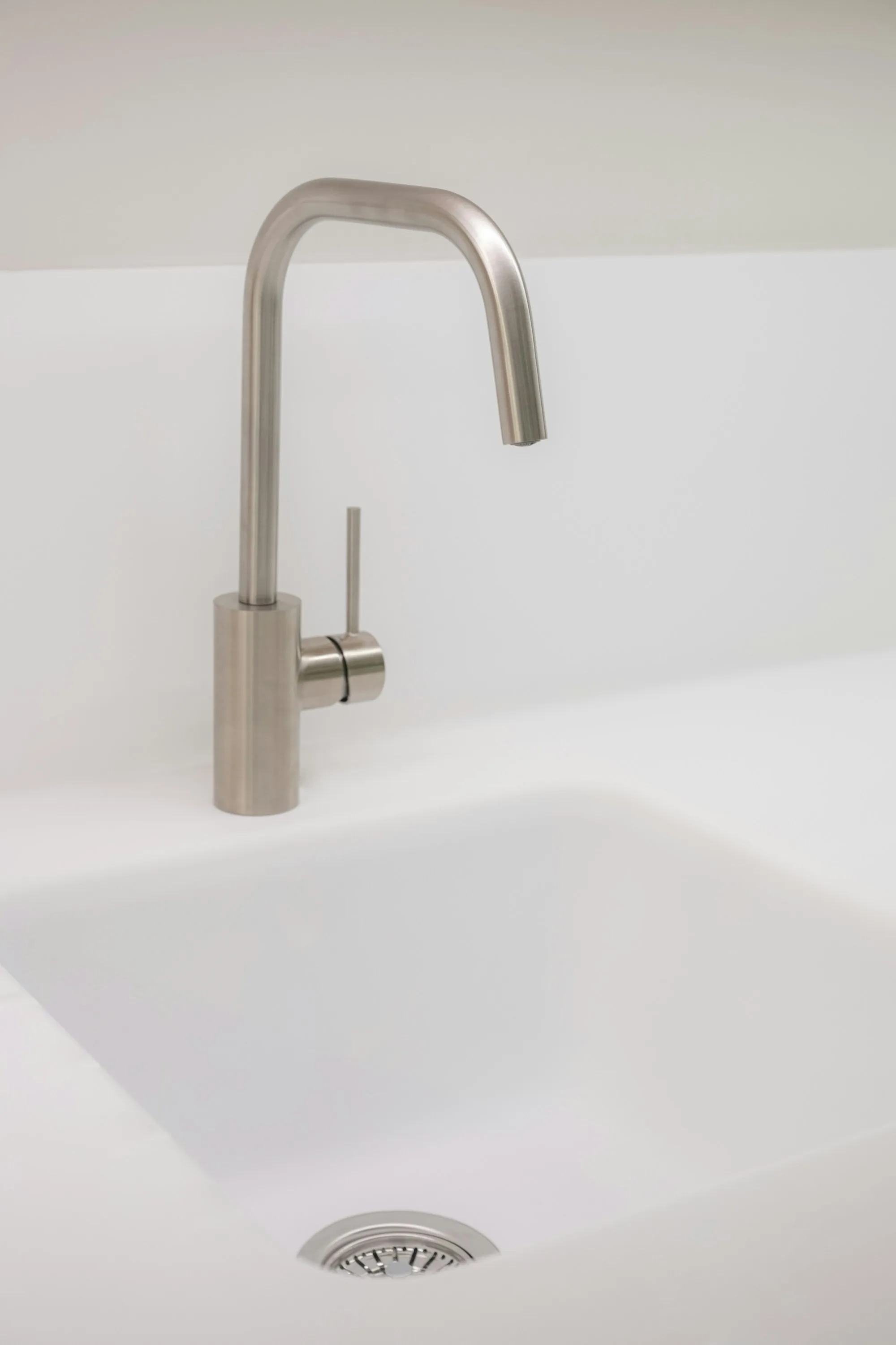 Slim brushed faucet over a clean white basin