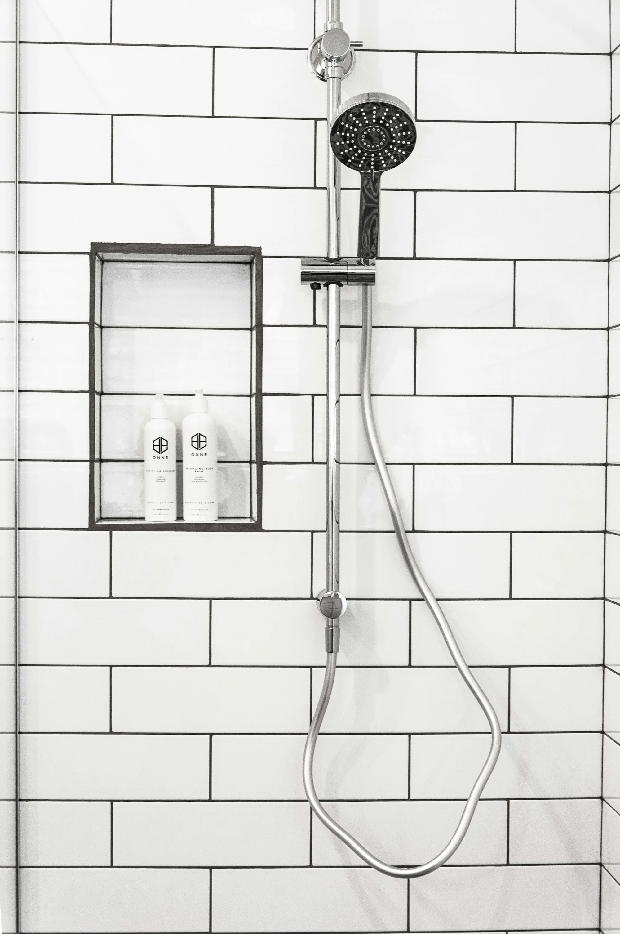 Shower fittings on a white tiled bathroom wall