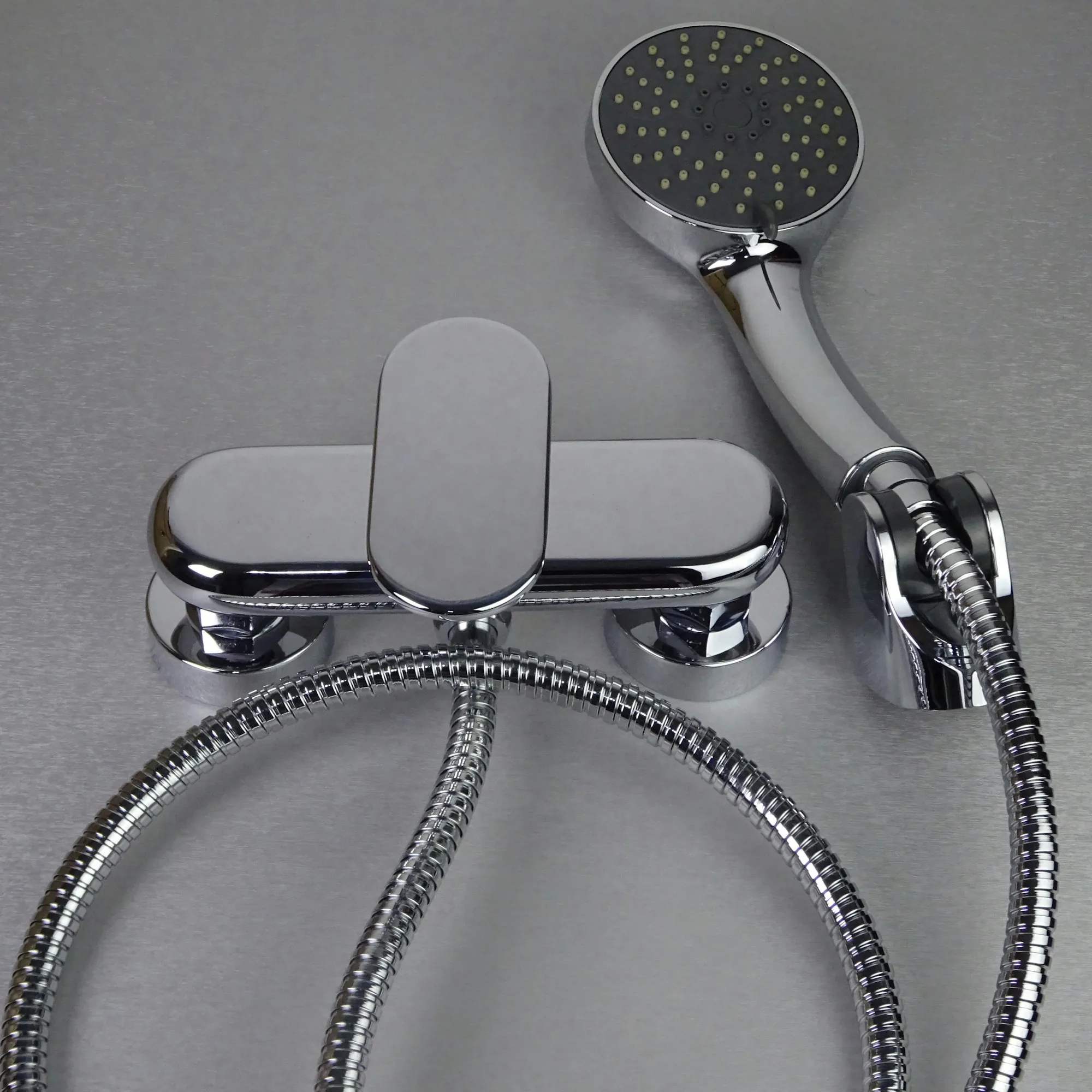 Chrome bath mixer and handheld shower fitted to a tiled wall