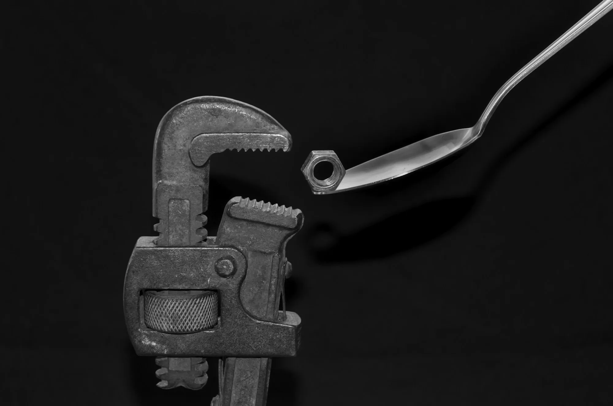 Pipe wrench and bent copper tube on a dark surface