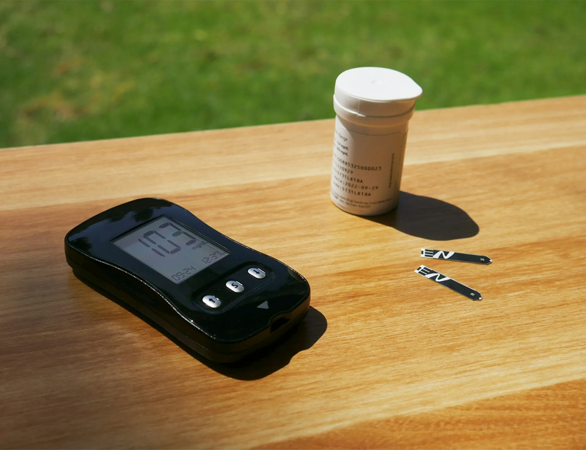 Handheld water meter and sample bottle on a wooden table