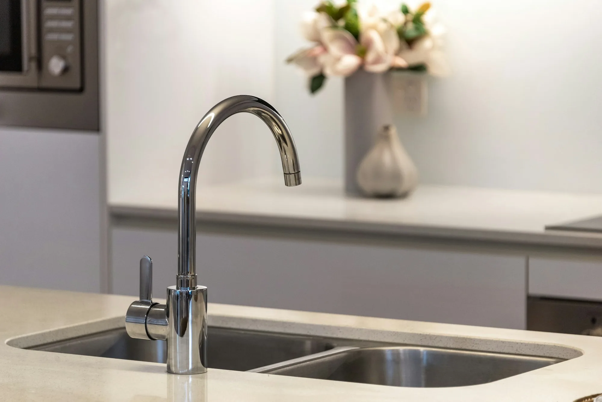 Kitchen sink and chrome faucet with flowers on the counter